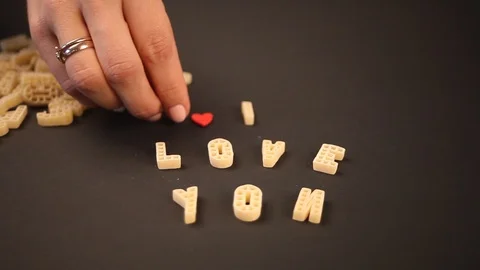 Woman's hand put heart-shaped red candy on black background Stock Footage 101644387