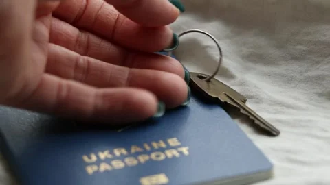 A woman's hand put the house keys next to the Ukrainian foreign passport Stock Footage 264374701