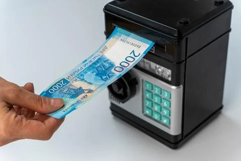 Woman's hand puts a 2000 banknote in a toy safe, Foto stock