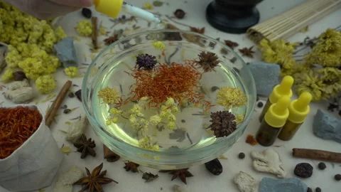 Woman's hand puts aromatic dried flowers and herbs to the glassware with a water Stock Footage 148378439