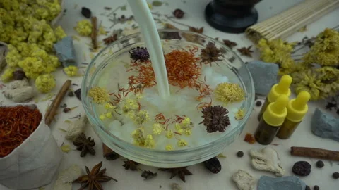 Woman's hand puts aromatic dried flowers and herbs to the glassware with a water Stock-Footage 148378526
