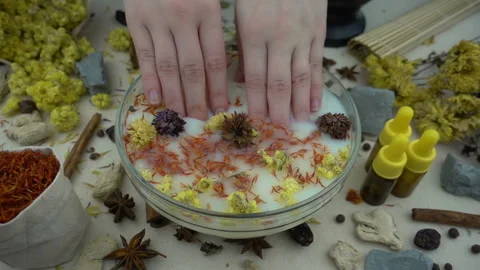 Woman's hand puts aromatic dried flowers and herbs to the glassware with a water Stock-Footage 148378527