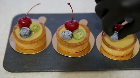 Woman's hand puts berries on a lemon tart cake. Cherry and blueberry dessert Stock Footage 102368879