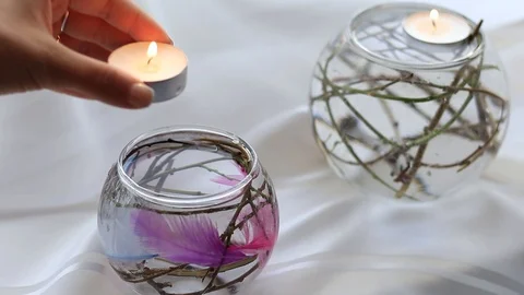 Woman's hand puts a candle in a flask with water and decorations Stock Footage 96986097