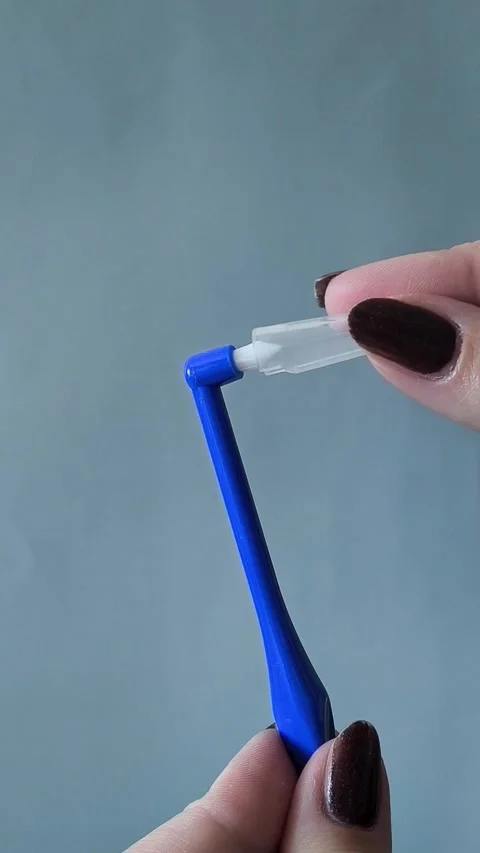 A womans hand puts on a cap on a single tuft toothbrush close-up. Oral hygiene 库存影片 329969503