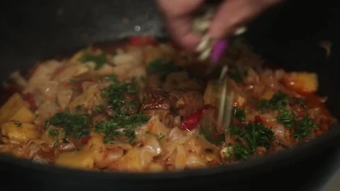 A woman's hand puts chopped garlic and herbs from a cutting board into a Stock Footage 262239449