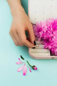 Woman's hand puts diamond ring in the jewellery box. Beautiful accessory on blue Stock Photos