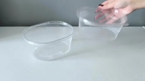 A womans hand puts disposable transparent containers on the table. Containers Vidéo 330156793