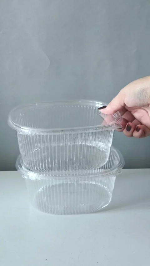 A womans hand puts disposable transparent containers on the table. Containers Vidéo 330156818