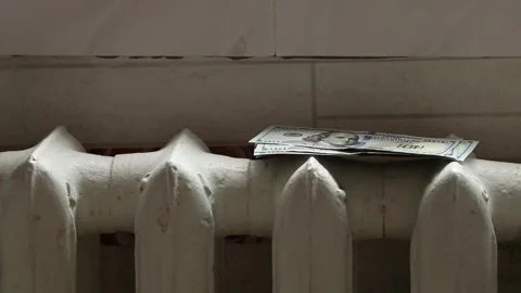 A woman's hand puts dollars on an old cast iron radiator in an apartment Stock Footage 265091683