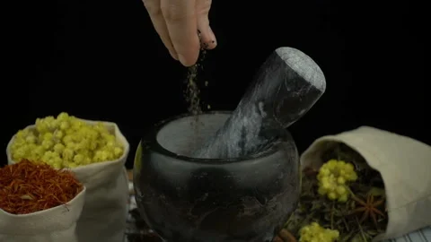 Woman's hand puts dry basil petals into the granite mortar with pestle in slow m Stock Footage 132667241