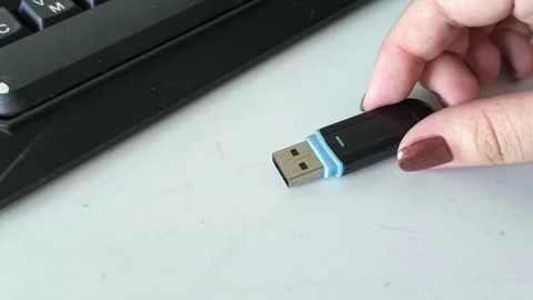 A womans hand puts the flash drive on the table, near the laptop. Data retention Stock Footage 320523655