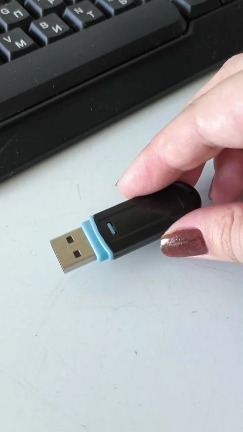 A womans hand puts the flash drive on the table, near the laptop. Data retention Stock Footage 320523699