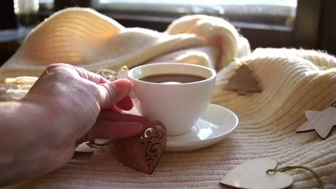 Womans hand puts a mug black coffee on a warm scarf with wooden Christmas toys Stock Footage 220567116