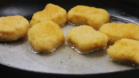 A woman's hand puts nuggets on a frying pan with oil. Close-up 库存影片 296908765