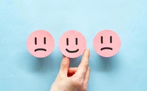 A woman's hand puts or selects a paper pink sticker with a happy face. Conc.. Stock Photos