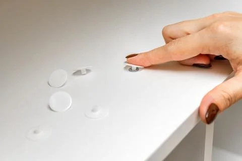 A woman's hand puts a plastic cap on a Euro screw. Stock Photos