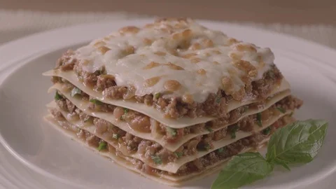 A woman's hand puts a plate on the table with a piece of tasty, meat lasagna. Stock Footage 83723149