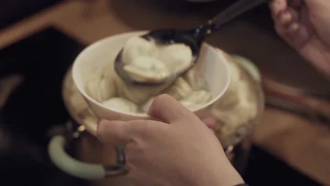 Woman's hand puts portion of pelmeni and broth into ceramic bowl. Video stock 180428905