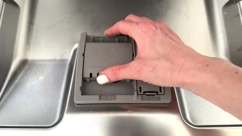 A woman's hand puts a tablet in the dishwasher before washing dishes. close-up Stock Footage 239923937
