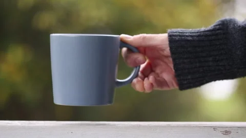 Woman's hand puts tee mu, autumn background Video stock 252146122