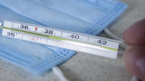 Womans  hand puts a thermometer with a temperature of 38 on a background Stock Footage 129662011