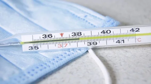 Womans  hand puts a thermometer with a temperature of 38 on a background Stock Footage 129662457
