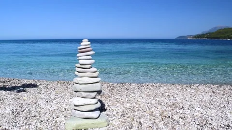 Woman's hand puts top pebble on a turret made of stones. Beautiful clean pebble  Stock Footage 308233014