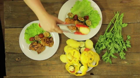 A woman's hand puts vegetables into a ready-made chicken from a grill pan in a Stock Footage 112716861
