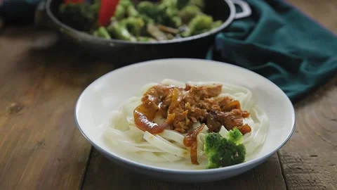 A woman's hand puts vegetables on udon with meat in yakiniku sauce Stock Footage 156571776