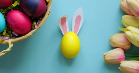 A woman's hand puts a yellow Easter egg with rabbit ears on the table Video stock 235772712