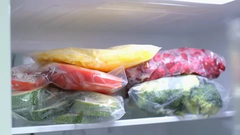 A woman's hand puts zip lock bag with yellow carrots into the refrigerator Vidéo 341368514