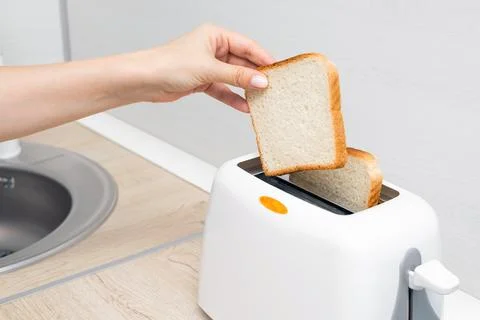 Woman's hand putting bread into the toaster, close-up Stock Photos