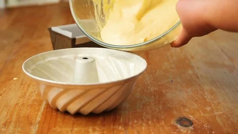 Woman's hand putting cake batter into baking container Stock Footage 76099656