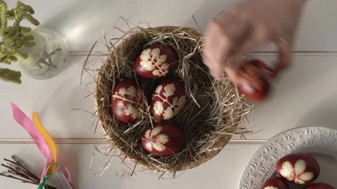 Woman's hand putting Easter eggs dyed with onion peels into a wicker basket Video stock 171833484