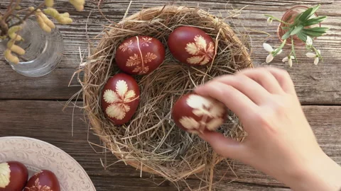 Woman's hand putting homemade Easter eggs dyed with onion peels into a basket Stock Footage 170199440
