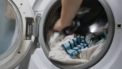 A woman's hand quickly puts dirty laundry into an automatic washing machine Stock Footage 168182036