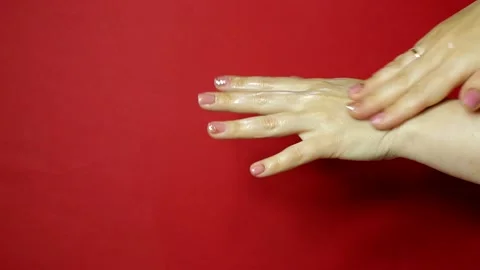 A woman's hand on a red background, rubs cream, self-massage, peeling prevention Vídeo Stock 160895203