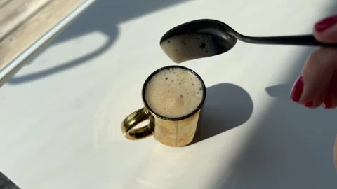 Woman's hand with red manicure gently stirring the creamy foam in a cup Stock Footage 342069722