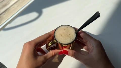 Woman's hand with red manicure gently stirring creamy white foam in a cup Stock Footage 342071519