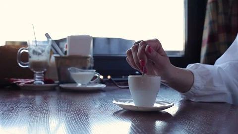 A woman's hand with a red manicure interferes with a spoonful of coffee at a caf 库存影片 114394987