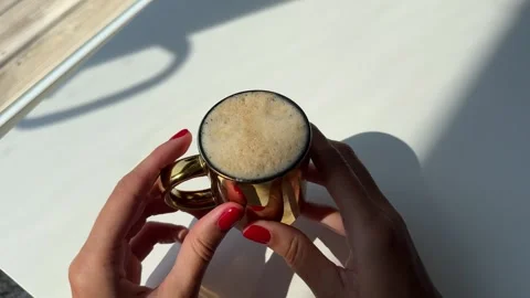 Woman's hand with red manicure picking up a cup of coffee from a white table Stock Footage 342069622