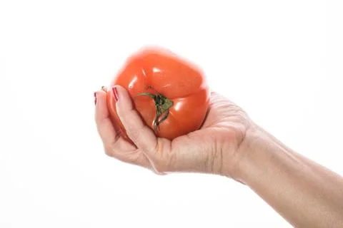 Woman's hand with red nail squeezing tomato on a white background Stock Photos