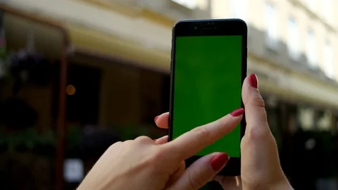 Woman's hand with red nails holding black phone with vertical green screen near  Stock Footage 112349943