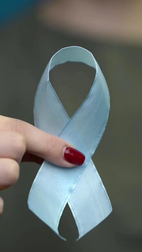 A woman's hand with red nails holds a light blue satin awareness ribbon Stock Footage 345137348