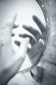 Womans hand reflected in round mirror Stock Photos