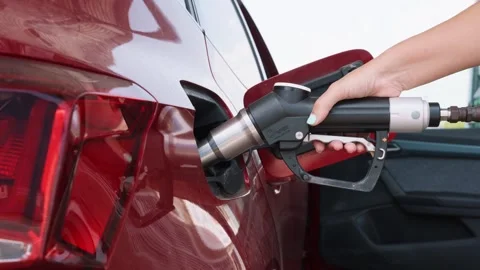 Woman's hand refueling a red car with lpg gas nozzle during oil crisis Stock Footage 343162459