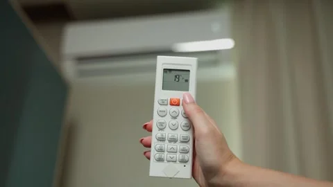 Woman's hand regulating the air conditioner with the remote control. Stockbeeldmateriaal 252748520
