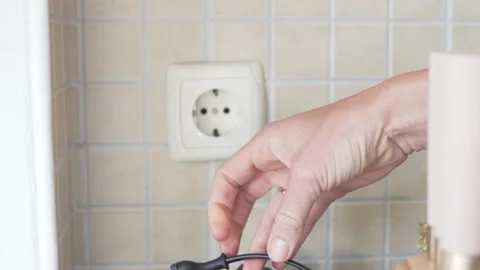 A woman's hand removes the plug from the socket Stock Footage 234407950