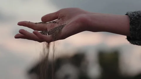 A woman's hand with a ring releases sand and stone pebbles. Stock Footage 260210596